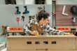 © BESTIMAGE - One Strong confident young aged women carpenter standing aim at wood plank in workshop. Latin female carpenter entrepreneur working craft with wood diy tool in workbench shop carpentry
