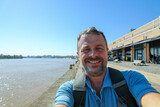 Fototapeta  - middle aged man taking a selfie phone on holidays bordeaux quay background