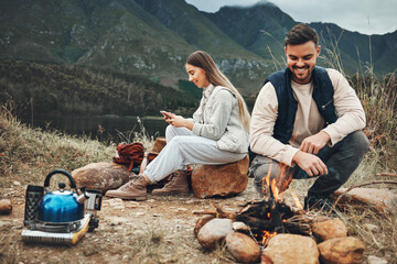 Poster - Wood, nature and couple with fire on a camp on a mountain for adventure, weekend trip or vacation. Stone, sticks and young man and woman making a flame or spark in outdoor woods or forest for holiday