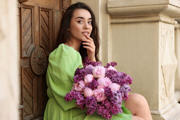 Poster - Beautiful woman with bouquet of spring flowers near building outdoors