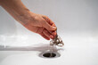 © DimaBerlin - Hand pulls hair out of bathroom drain. Female palm extracts shock of hair from siphon in bathroom. Water drain hole clogged with hair clump. Close up. Cleaning shower polluted sewerage system.