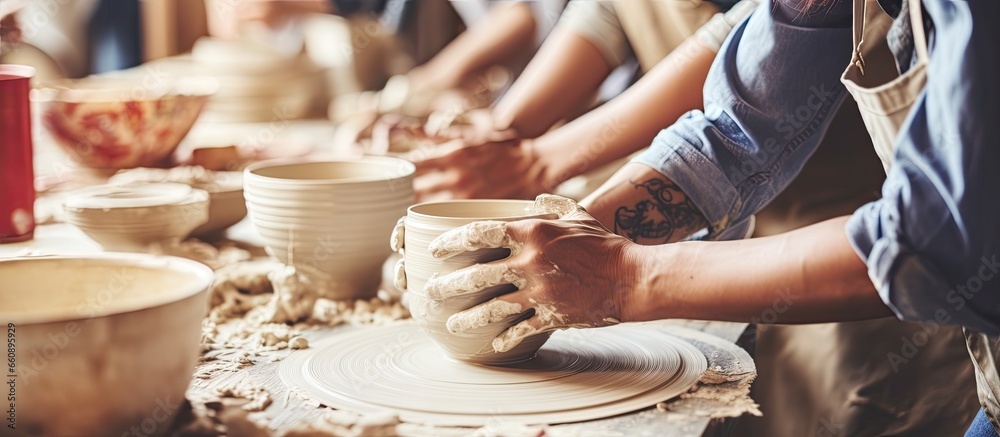 Young people working on pottery wheel together in a ceramics workshop ...