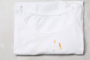 Wall Mural - Dirty t-shirt with stains of sauce on light grey marble table, top view