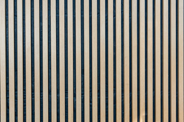 A three dimensional vertical seamless pattern of modern wall paneling with vertical wooden slats for a wall. A light brown wooden slats texture for interior decoration.