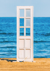  Conceptual photo with a wooden door placed on a beach at the seashore. Summer vacation theme wallpaper