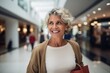 © Carmen Martín J. - Mujer madura sonriente en un centro comercial visitando las tiendas en rebajas.