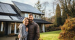 Man and woman standing in front of house with solar roof or photovoltaic system - topic green electricity and energy transition
