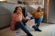 © Marko Geber - Young mixed couple going over bills and payments together on the floor of the kitchen at their home