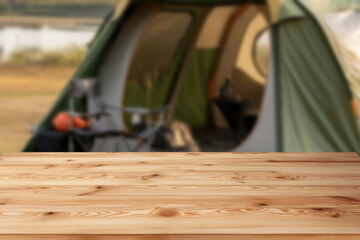 Wall Mural - Wooden table top on blur tent camping travel tent and grass field.Fresh and Relax concept.For montage product display or design key visual layout.View of copy space.