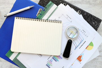 Wall Mural - business concept. Blank notepad on office folders and financial charts on office wooden table. close-up