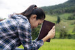 Woman praying on holy scripture in field during beautiful sunris