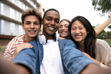 Happy carefree group of friends taking a selfie laughing.Multiracial young relaxed people having fun and taking pictures outside.