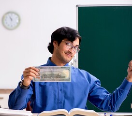 Wall Mural - Young male teacher in front of chalkboard