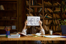 Tired Girl Student Lying On Home Desk Holding Placard With Help Word