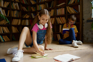 Little schoolchildren spending time at home library