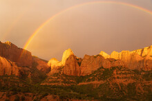 A Rainbow Arcs Over The Towering Cliffs Of Kolob Canyon In Zion Nat. Park Utah, And The Light Paints The Cliffs With Warm Glowing Color. As A Break Forms In The Clouds West Of The Canyon At Sunset. 