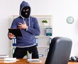 Male thief in balaclava in the office