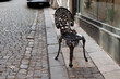 an unusual iron chair stands alone on the street