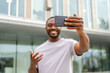 © Юлия Завалишина - African American man holding smartphone having video chat on urban street in city. Guy blogger chatting with best friends in social network. Man having virtual meeting online chat video call outdoor