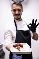 Wall Mural - Arabe chef holding a tray with a cooked octopus arm while saying ok with his hand