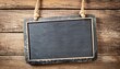Blank chalkboard sign hanging from old wooden background