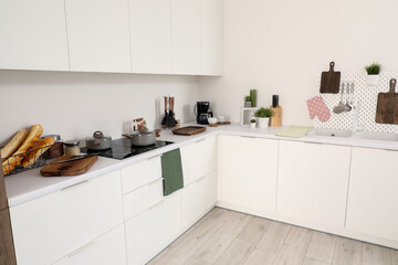 Canvas Print - Interior of light kitchen with cutting boards, pegboard, sink and electric stove on white counters