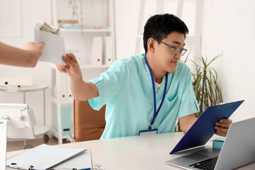 Canvas Print - Male Asian doctor taking bribe in clinic