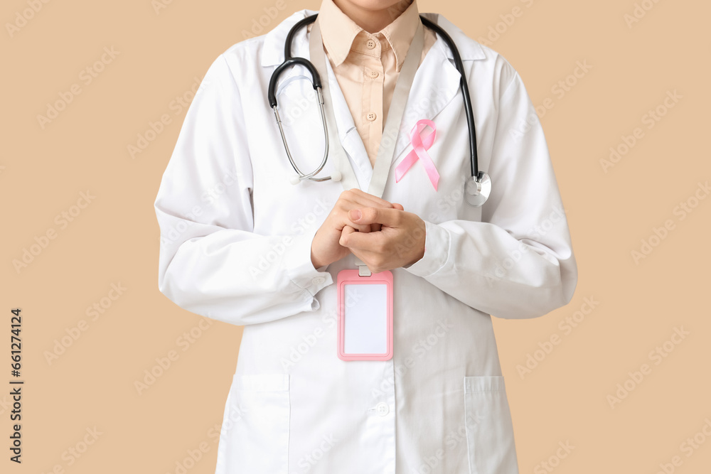 Female doctor with pink ribbon on beige background. Breast cancer awareness concept