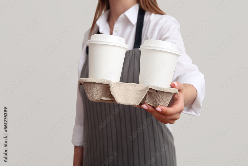 Woman with takeaway paper cups and holder on light background