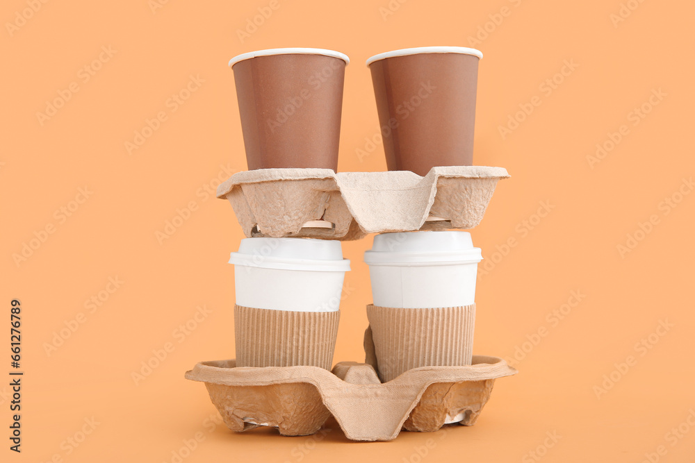 Takeaway paper cups with holders on beige background