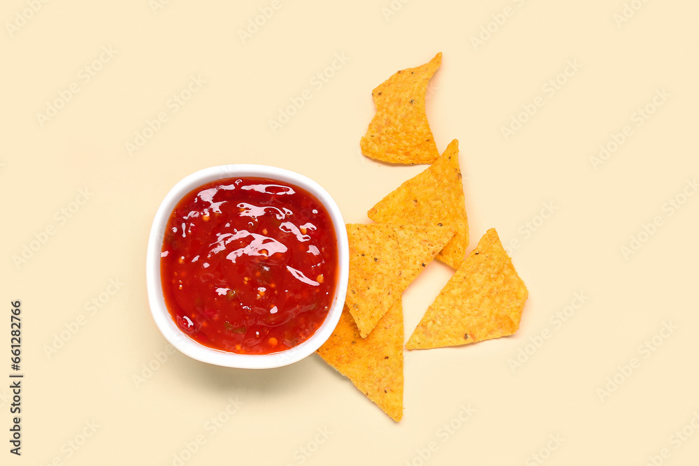 Bowl with tasty salsa sauce and nachos on yellow background