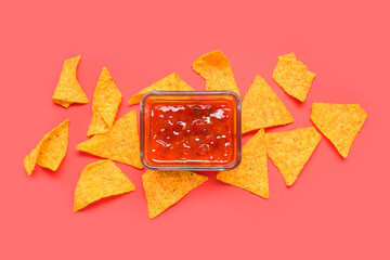 Bowl with tasty salsa sauce and nachos on red background