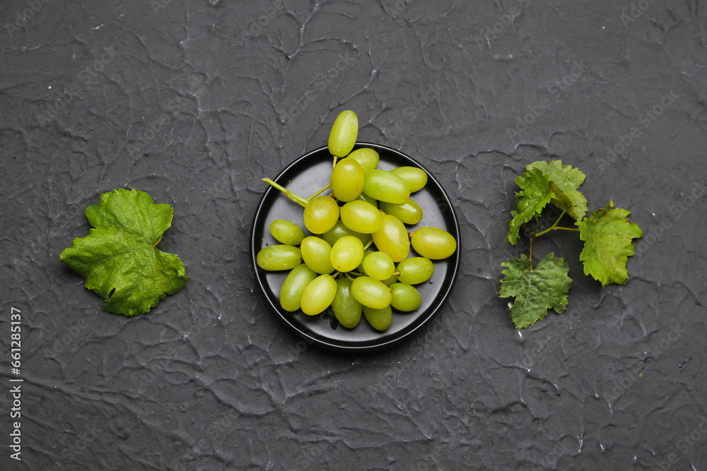 Juicy white grapes in a bowl on black background, top view