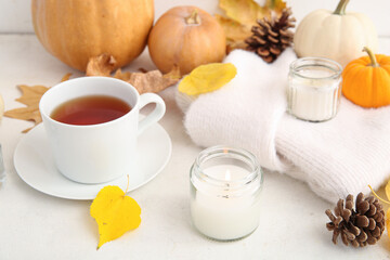 Wall Mural - Cup of tea, autumn leaves, sweater and burning candles on white background