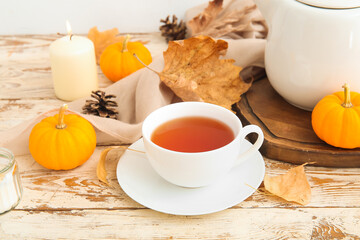 Wall Mural - Cup of tea, pumpkins, burning candles and autumn leaves on table