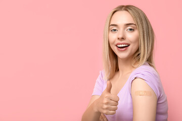 Canvas Print - Young woman with medical patch on arm showing thumb-up against pink background. Vaccination concept