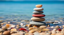 Pile Of Smooth Stones Stacked On A Pebbly Beach, Symbolizing Balance And Stability, With The Ocean Backdrop