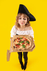 Poster - Young woman dressed for Halloween as pirate with tasty pizza on yellow background