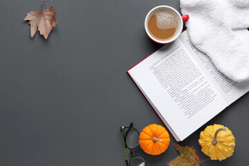 Wall Mural - Composition with open book, cup of coffee, socks and autumn decor on dark background