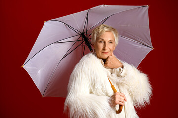 Canvas Print - Beautiful mature woman with umbrella on red background