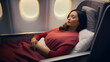 Young woman passenger sleeping on the seat with a pillow and blanket on a flight in the business class cabin