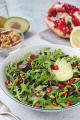 Wall Mural - A plate with green rocket salad with pomegranate and avocado