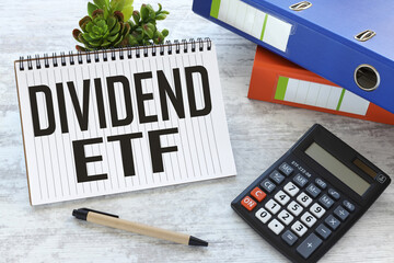 dividend ETF text on a notepad near a plant in a pot. blue folder