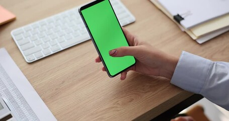 Woman holding smartphone with green screen in office. Mobile applications and mobile phone use
