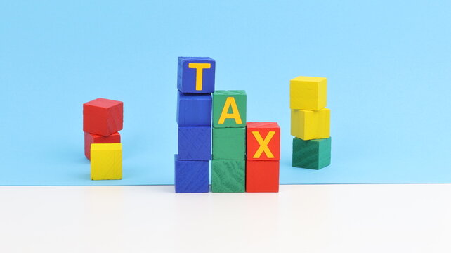 The word Tax written with wooden blocks and colored sheets, on the table, copy space.