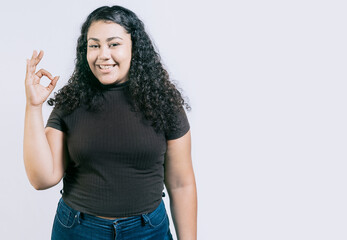 Smiling young woman gesturing ok isolated. Happy girl with thumbs up isolated. Smiling people showing ok gesture isolated