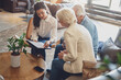 © lordn - A hotel or travel agency representative is talking with a senior tourist couple offering various tourist services