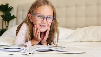 Wall Mural - surprise excited toddler in glasses reading interesting encyclopedia new facts information. looks at camera, opens eyes and mouth Developing smart children. fantasy for kids. Kid emotion