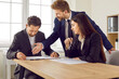 © Studio Romantic - Group of business people or company employees sitting at the desk discussing something on workplace, reaching agreement and going signing a contract. Coworkers having a meeting in office.