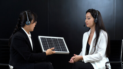 asian master of ceremonies or journalist in suit giving interview to businesswoman or celebrity with solar cell to renewable energy power energy and eco environment concept in  studio tv show on air